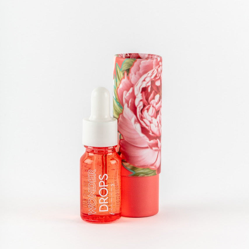Coral dropper bottle with floral packaging on a white background